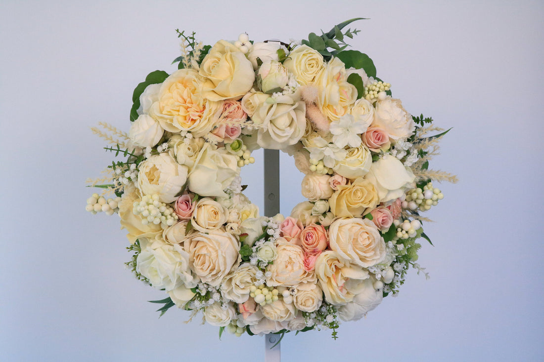 Ivory Romance faux floral wreath with cream and ivory blooms and layered greenery on a pale blue background