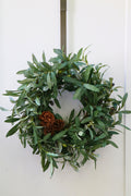 Faux olive wreath with green leaves, decorative olives and a cluster of brown pinecones.