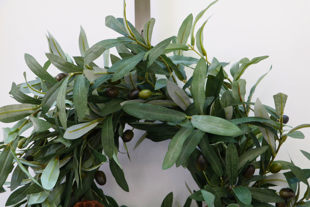 Faux olive wreath with green leaves, decorative olives and a cluster of brown pinecones.