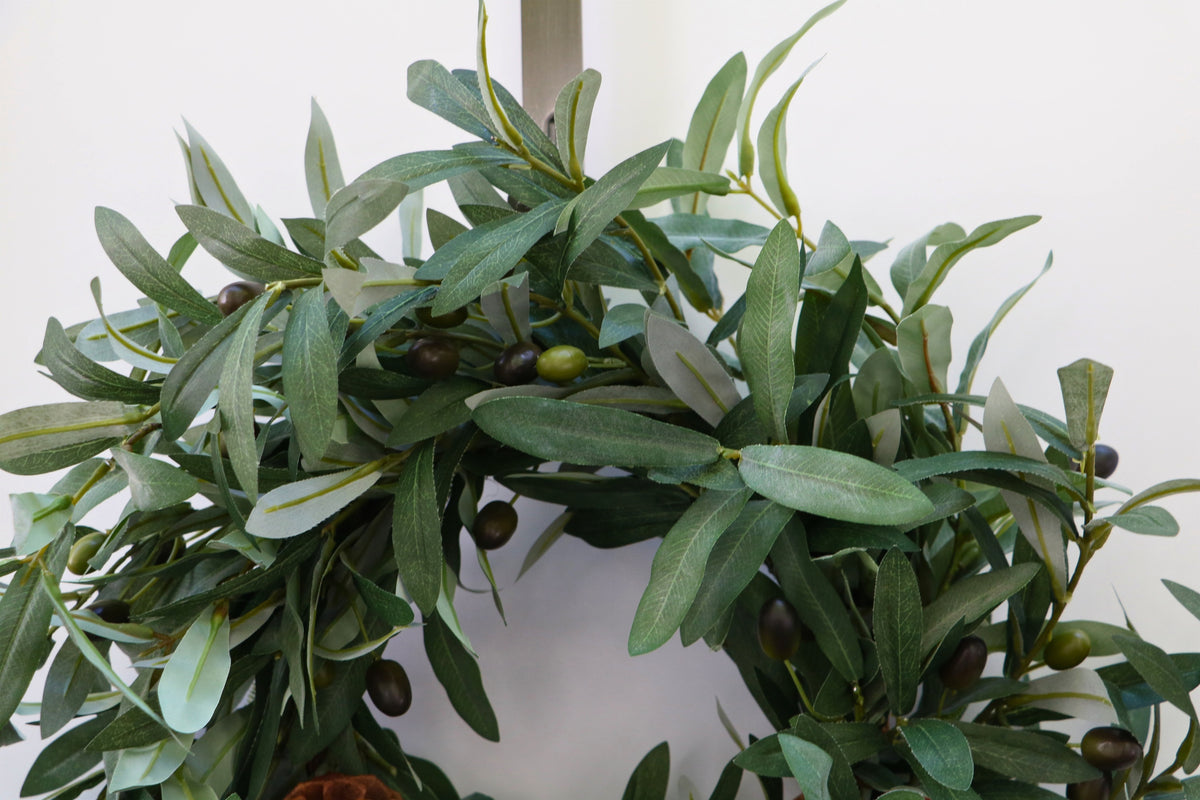 Faux olive wreath with green leaves, decorative olives and a cluster of brown pinecones.