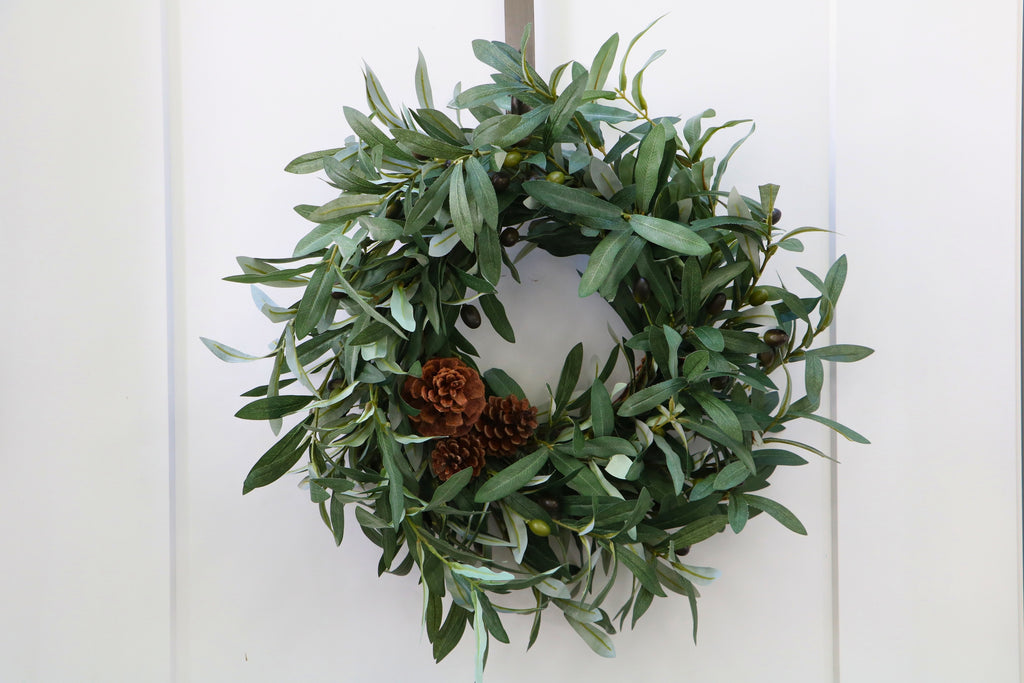 Faux olive wreath with green leaves, decorative olives and a cluster of brown pinecones.